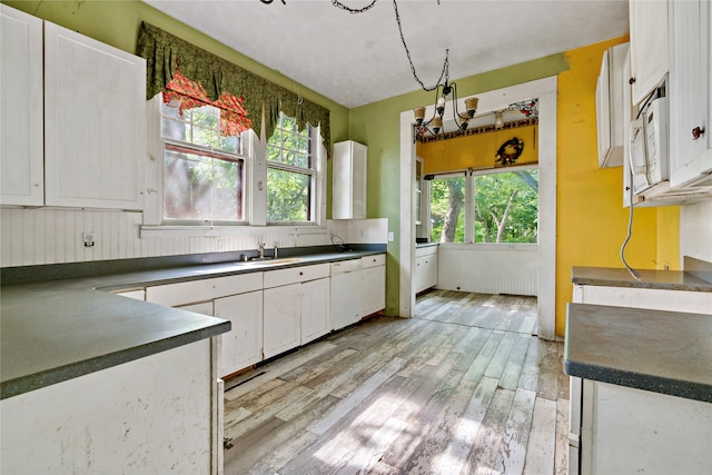 kitchen with a healthy amount of sunlight, white appliances, light hardwood / wood-style floors, and white cabinetry