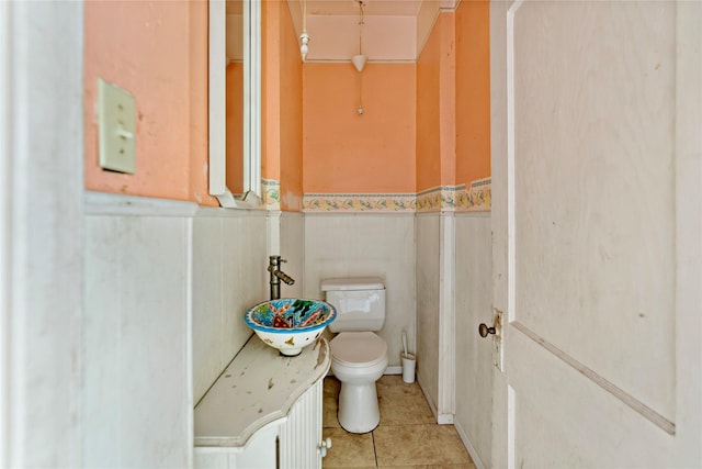 bathroom with toilet, tile patterned flooring, and sink