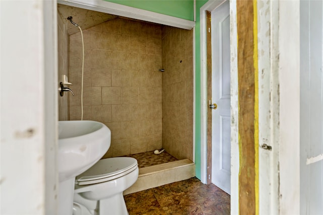 bathroom with tile floors, a tile shower, and toilet