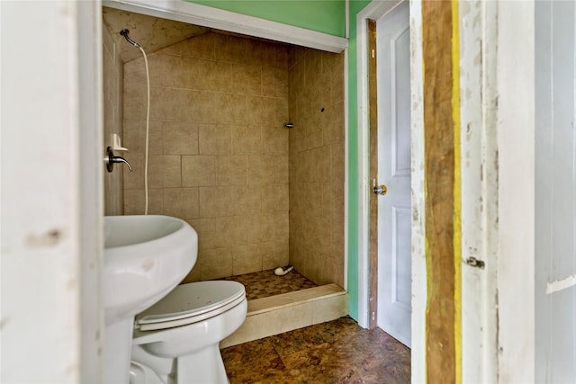 bathroom featuring toilet and a tile shower