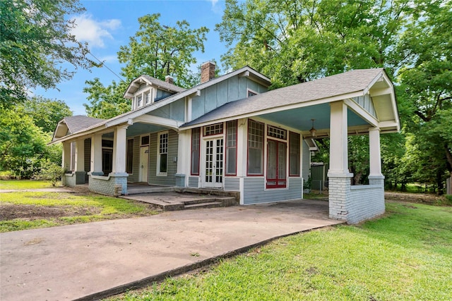 craftsman-style house featuring a porch, french doors, and a front lawn