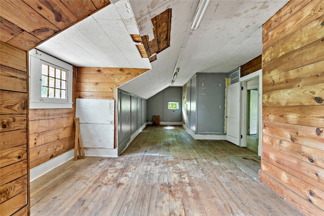 bonus room featuring vaulted ceiling, wood-type flooring, and wood walls