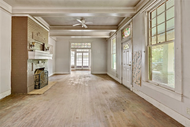 unfurnished living room featuring ceiling fan, beam ceiling, a brick fireplace, wood-type flooring, and brick wall