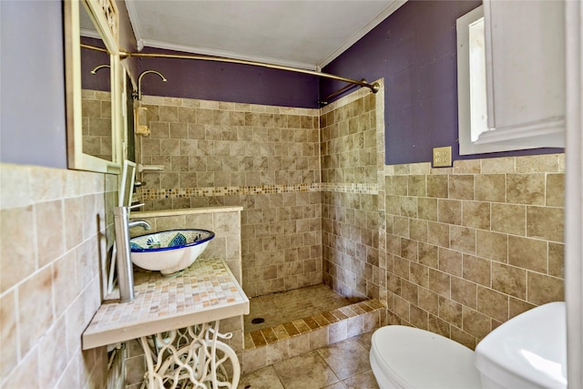 bathroom with toilet, sink, tile walls, a tile shower, and tile patterned flooring