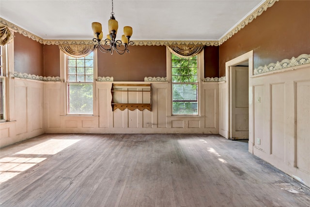 unfurnished dining area with a healthy amount of sunlight, hardwood / wood-style floors, and a chandelier