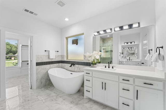 bathroom featuring separate shower and tub, vanity, and tile walls