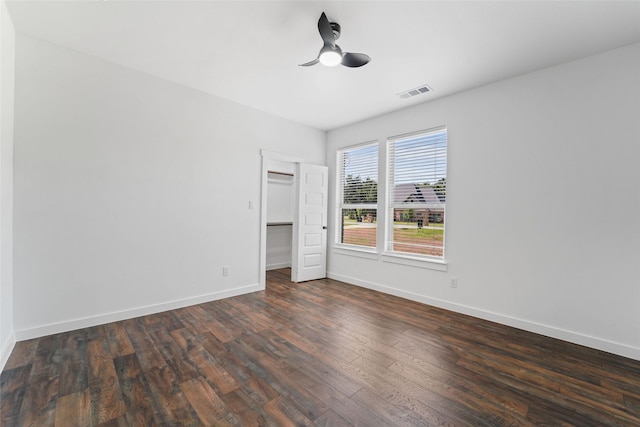 unfurnished bedroom with ceiling fan, a closet, a spacious closet, and dark hardwood / wood-style floors