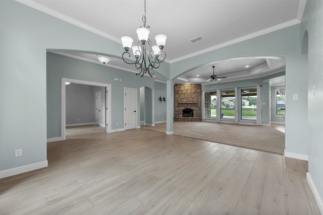 unfurnished living room featuring light wood-type flooring, ceiling fan with notable chandelier, a fireplace, and ornamental molding