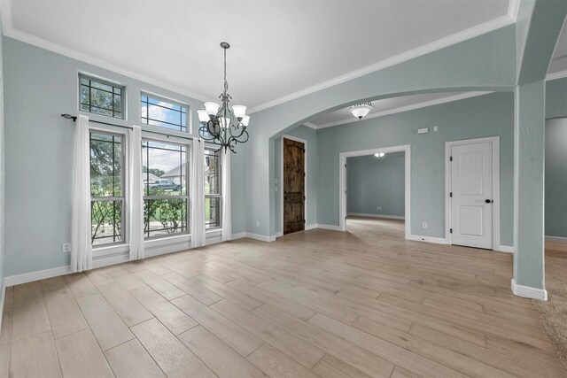 empty room with a chandelier, crown molding, and light hardwood / wood-style flooring