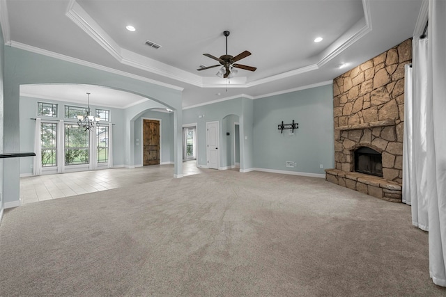 unfurnished living room featuring light colored carpet, ceiling fan with notable chandelier, a stone fireplace, and a raised ceiling