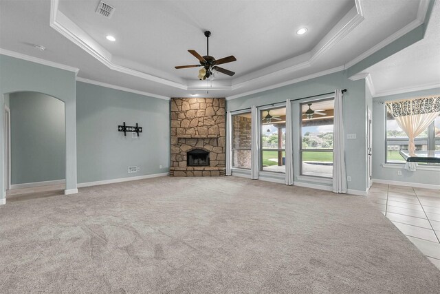 unfurnished living room with a fireplace, crown molding, light colored carpet, a raised ceiling, and ceiling fan