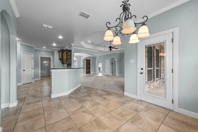 interior space with ceiling fan with notable chandelier, pendant lighting, crown molding, and light tile patterned flooring