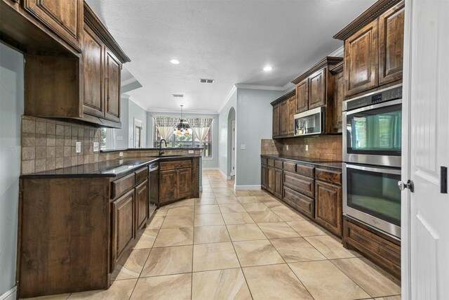 kitchen featuring dark stone countertops, ornamental molding, stainless steel appliances, and decorative backsplash