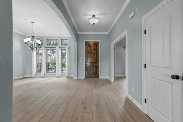 entryway with crown molding, a notable chandelier, and light hardwood / wood-style floors