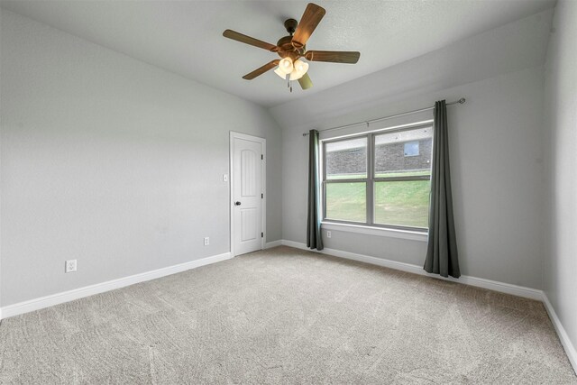 spare room with vaulted ceiling, light colored carpet, and ceiling fan