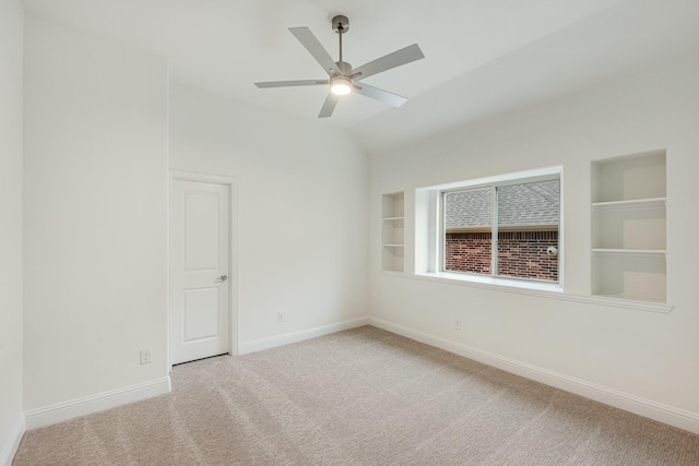 carpeted spare room with ceiling fan, lofted ceiling, and built in features