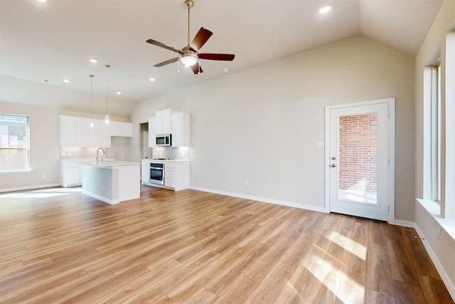 unfurnished living room featuring sink, high vaulted ceiling, light wood-type flooring, and ceiling fan