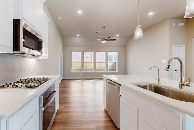 kitchen with appliances with stainless steel finishes, sink, light stone counters, and light hardwood / wood-style floors