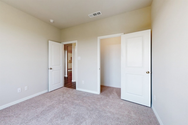 unfurnished bedroom featuring a closet and light colored carpet