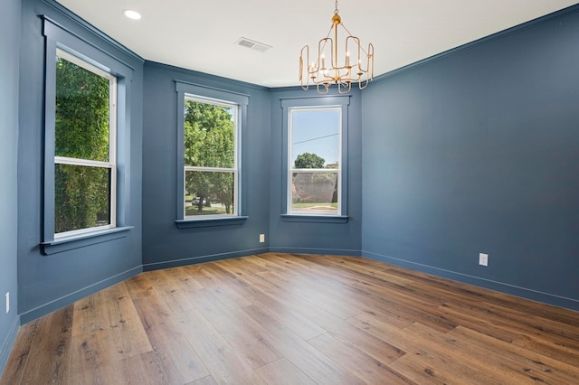 unfurnished room with crown molding, wood-type flooring, and a notable chandelier