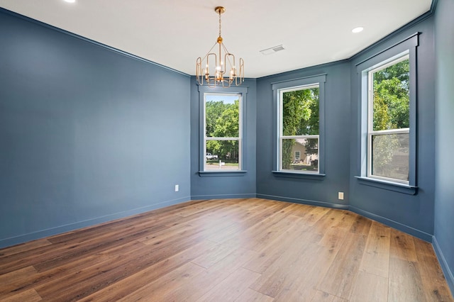 spare room with a chandelier, wood-type flooring, and ornamental molding