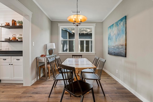 dining space with crown molding, dark wood-type flooring, and an inviting chandelier