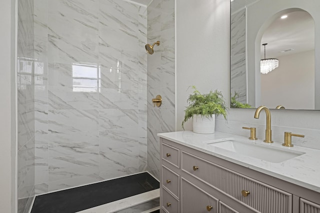 bathroom with a tile shower and vanity