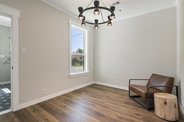 sitting room with ornamental molding, dark wood-type flooring, and a chandelier