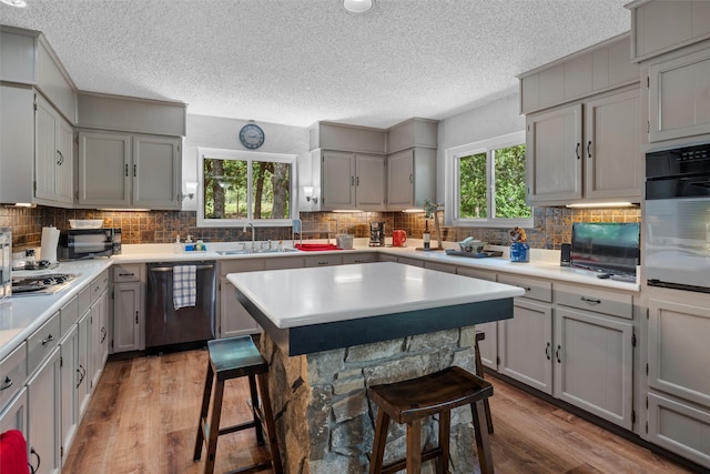 kitchen featuring gray cabinets, a kitchen bar, sink, and appliances with stainless steel finishes