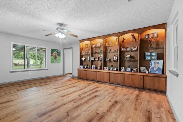 bar with ceiling fan, light hardwood / wood-style flooring, and a textured ceiling