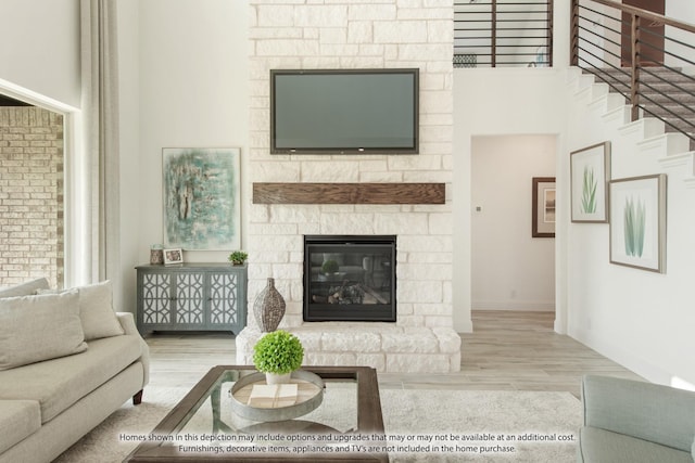 living room with light hardwood / wood-style floors and a stone fireplace