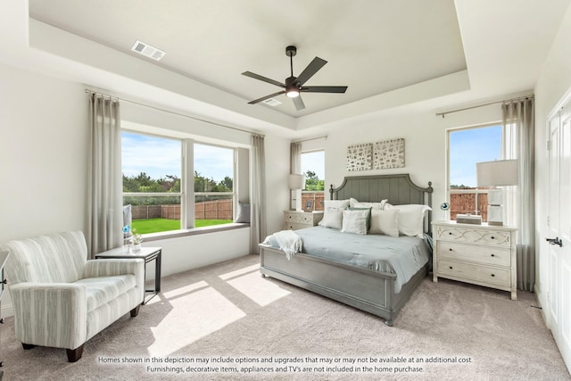 bedroom featuring ceiling fan, a raised ceiling, and light colored carpet