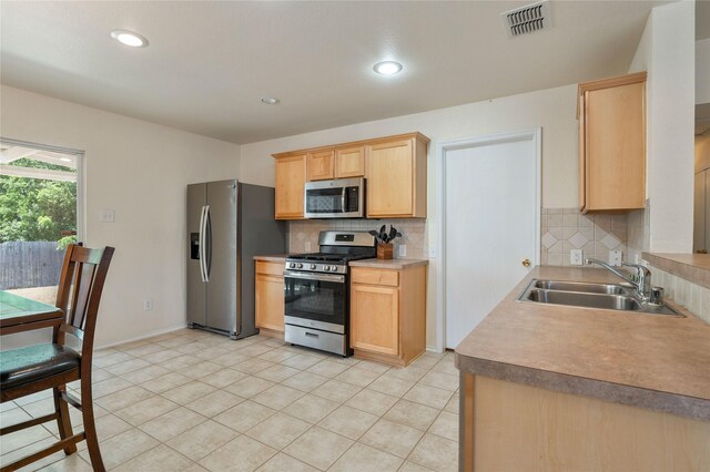 kitchen with tasteful backsplash, light tile flooring, light brown cabinetry, sink, and appliances with stainless steel finishes