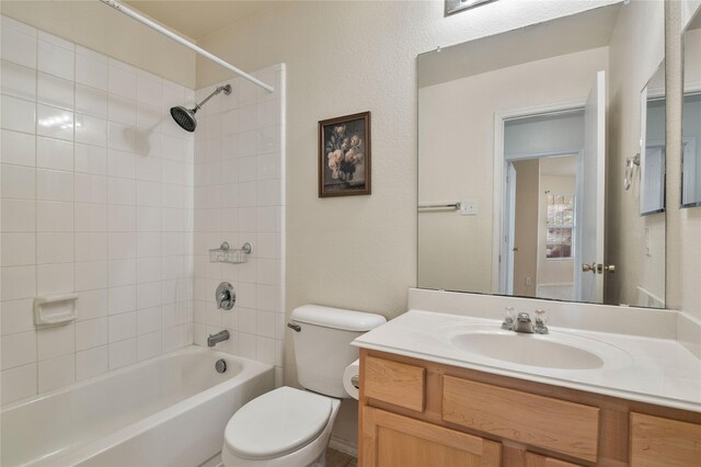 full bathroom with tiled shower / bath, toilet, and vanity