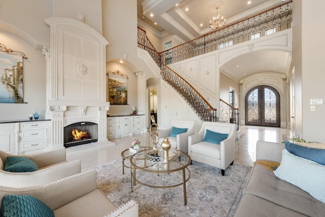 living room with a notable chandelier, ornamental molding, french doors, and a high ceiling