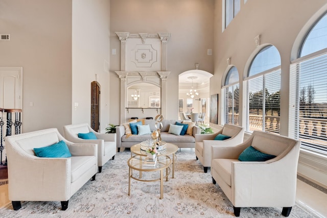 living room with a high ceiling, plenty of natural light, and a notable chandelier