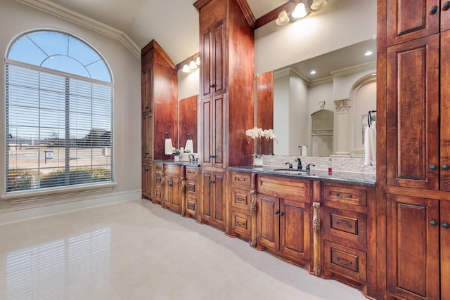 bathroom featuring vanity, a wealth of natural light, ornamental molding, and vaulted ceiling