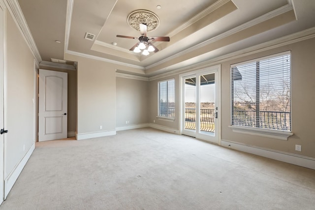 carpeted empty room featuring a raised ceiling, crown molding, and a wealth of natural light