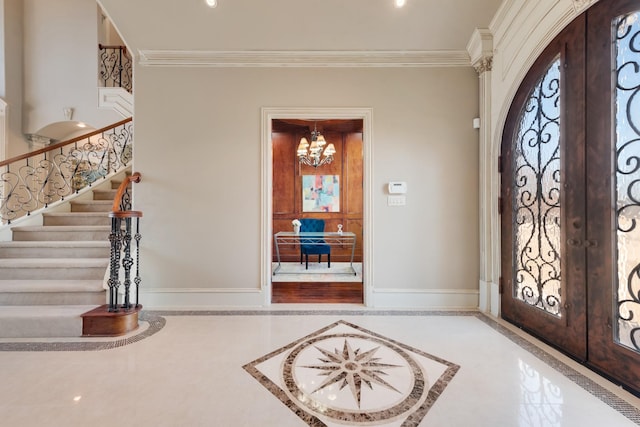 foyer entrance featuring crown molding, an inviting chandelier, and french doors