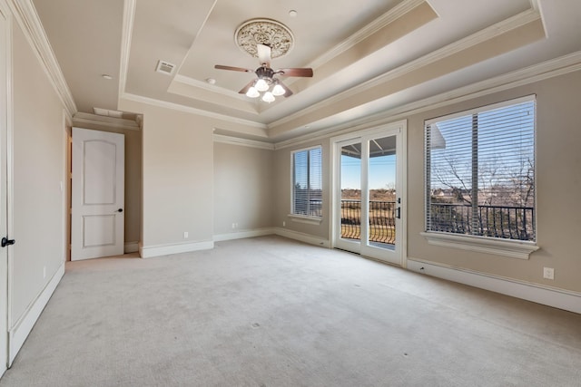 empty room featuring light colored carpet, ornamental molding, and a raised ceiling