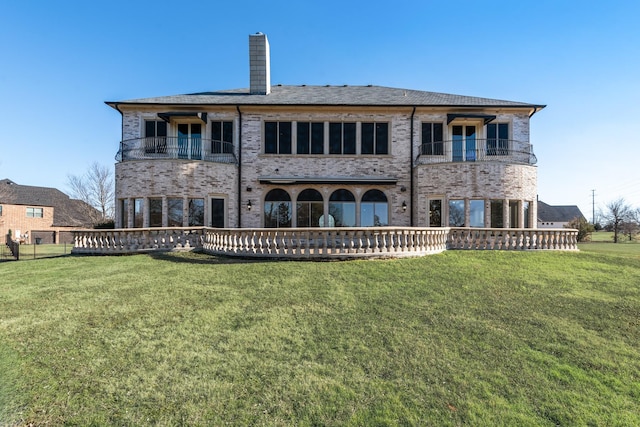 rear view of house with a balcony and a lawn