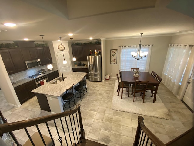 dining space featuring ornamental molding, sink, and a chandelier