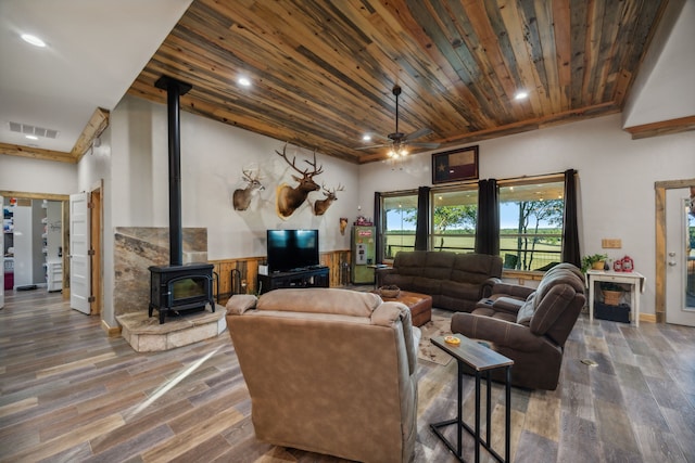 living room with ceiling fan, hardwood / wood-style floors, a wood stove, and wooden ceiling