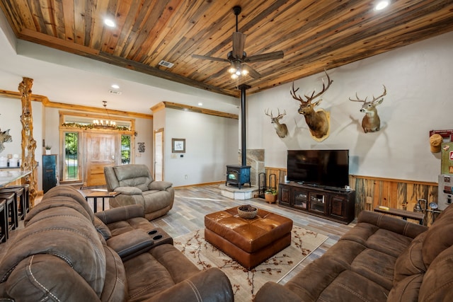 living room with ceiling fan, light hardwood / wood-style floors, a wood stove, and wooden ceiling