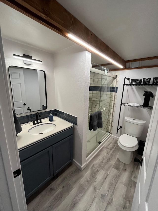 bathroom featuring hardwood / wood-style floors, vanity, toilet, and a shower with door