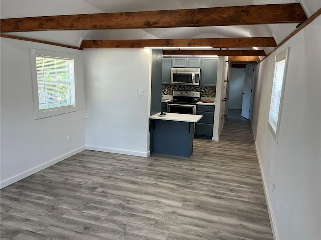 kitchen featuring gray cabinetry, hardwood / wood-style flooring, vaulted ceiling with beams, appliances with stainless steel finishes, and tasteful backsplash