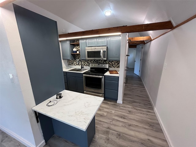 kitchen with sink, stainless steel appliances, tasteful backsplash, light hardwood / wood-style floors, and vaulted ceiling