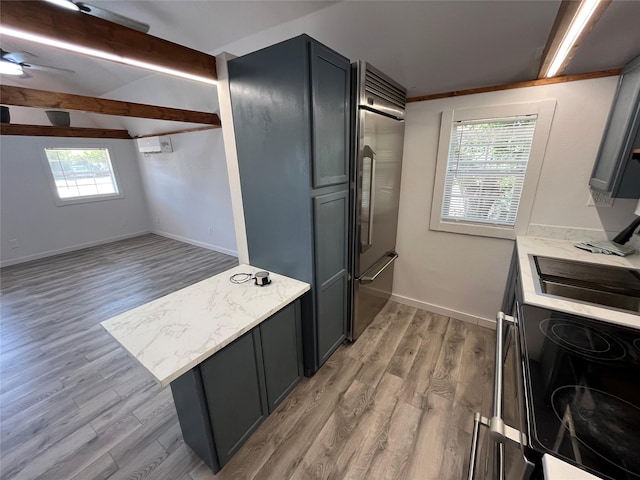 kitchen with plenty of natural light, stainless steel built in fridge, range, and light hardwood / wood-style flooring