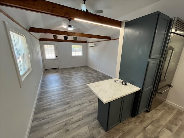 kitchen with light stone counters, ceiling fan, lofted ceiling with beams, and light wood-type flooring