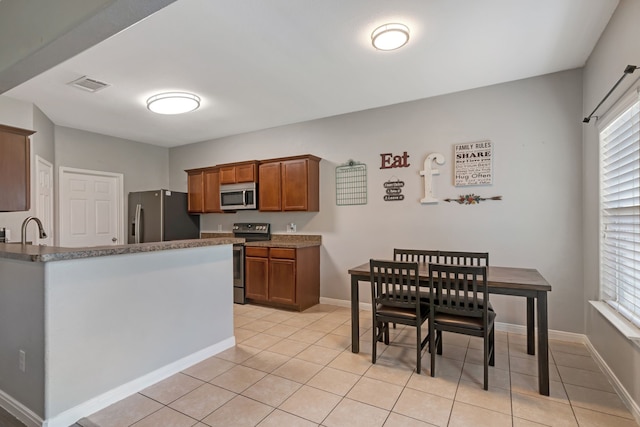 kitchen with stainless steel appliances, sink, light tile patterned floors, and a wealth of natural light